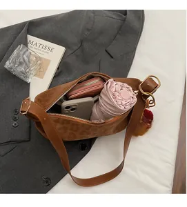Intérieur spacieux du sac à bandoulière léopard avec accessoires sur un costume gris