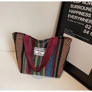 Macro view of multi-color woven tote bag with geometric ethnic patterns and red handles