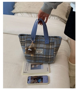 Detail of blue and brown plaid wool tote bag with a cute plush monster charm