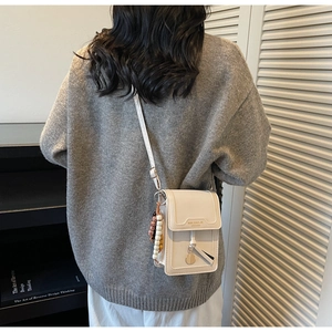 Close-up of a minimalist cream PU leather crossbody phone bag with beaded strap detail