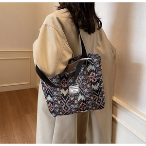 Détail d'un sac cabas tissé bohème aux motifs géométriques et bandoulière noire