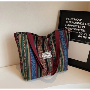 Detail of bohemian woven tote bag showing multicolor geometric patterns and red straps
