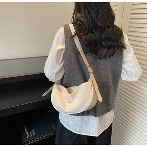 Détail de la bandoulière réglable et boucle argentée sur sac croissant crème