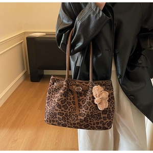 Model wearing a large leopard print tote bag with brown leather handles and bear charm