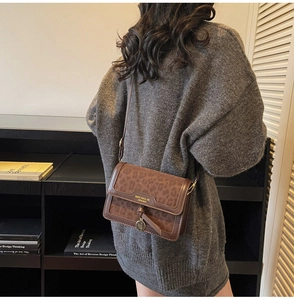 Détail du sac bandoulière léopard avec pendentif doré sur le rabat en cuir