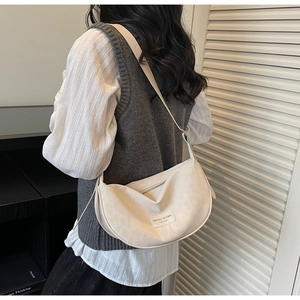 Détail d'un sac hobo crème avec texture mate et étiquette de marque sur un modèle