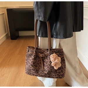 Detail of leopard and rose print tote bag with brown leather handles and plush bear charm