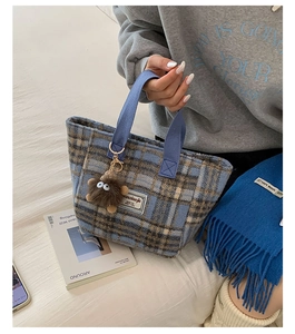 Blue and brown plaid wool tote bag detail with plush monster charm and brand tag