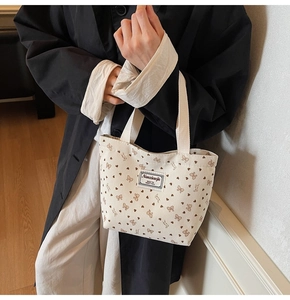 Detail of off-white corduroy tote bag with brown heart pattern and square label