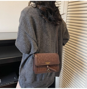 Détail du sac bandoulière vintage léopard avec pendentif en métal sur un pull gris