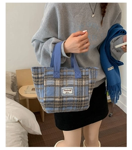 Close-up of blue and brown plaid wool tote bag with white woven label detail