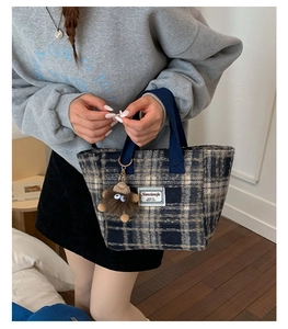 Detailed texture of blue plaid wool tote bag with a cute brown plush monster charm