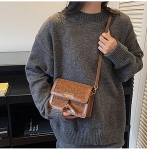 Détail du sac à motif léopard avec logo doré et bandoulière en cuir marron