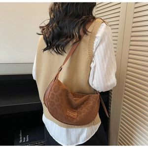Gros plan du sac hobo en daim marron avec motif léopard discret et bandoulière en cuir