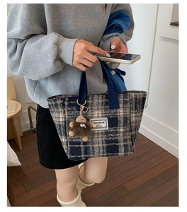 Detail of plaid tote bag in navy and khaki tweed with a plush brown charm