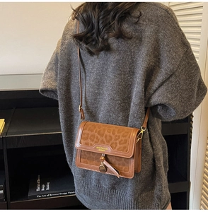 Détail du panneau léopard et emblème métallique sur le sac bandoulière en cuir brun