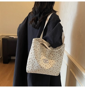 Détail d'un sac cabas en toile beige avec motifs papillons et cœurs sur l'épaule