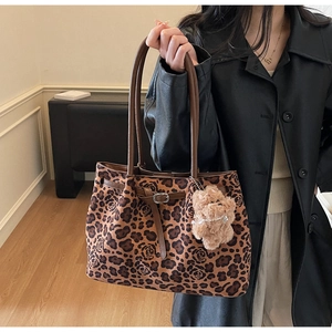 Lifestyle shot of a large leopard and rose print tote bag with a plush bear charm