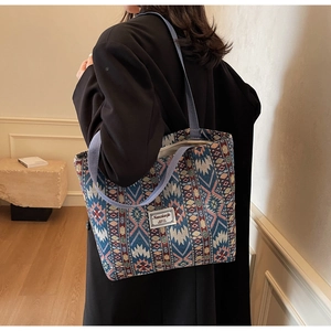 Gros plan d'un grand sac cabas ethnique aux motifs géométriques tissés porté à l'épaule