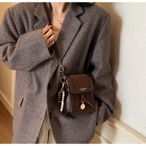 Detail of leopard print flap and Nan Xiao Jie branding on brown leather crossbody bag