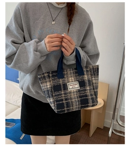 Detail of blue plaid wool tote bag with white woven label and sturdy canvas handles