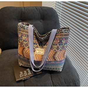 Detail of colorful ethnic woven tote bag featuring geometric patterns and purple handles