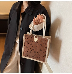 Détail du sac en lin avec motifs de cœurs, anses en corde et grand bouton décoratif