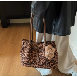Detail of leopard floral tote bag with brown leather handles and plush bear charm