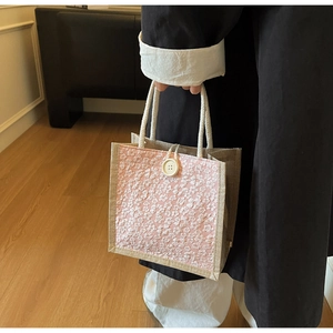 Close-up of pink linen lunch bag with white floral embroidery and woven rope handles