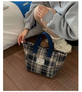 Close-up of a vintage plaid wool tote bag with woven straps in a cozy lifestyle setting