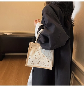 Détail du sac en lin avec imprimés nœuds et cœurs bruns et anses tressées blanches