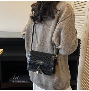 Gros plan du sac à bandoulière en léopard avec boucle dorée sur un pull gris élégant