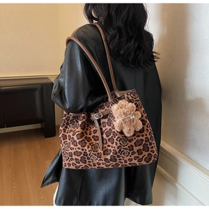 Detailed side view of leopard rose print tote bag with brown straps and plush bear charm