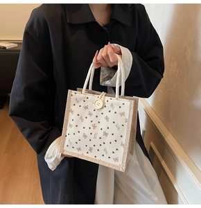 Détail du sac en lin avec motifs cœurs bruns, poignées en corde et fermeture à bouton