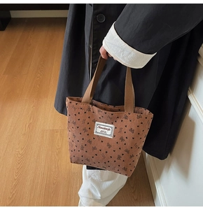 Detail of brown corduroy tote bag with black heart and bow prints and brand label