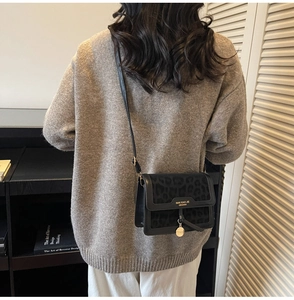 Détail d'un sac à rabat léopard avec plaque logo dorée et franges en cuir tressé