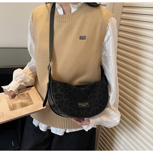 Détail du sac croissant léopard noir sur mannequin montrant le logo et la texture