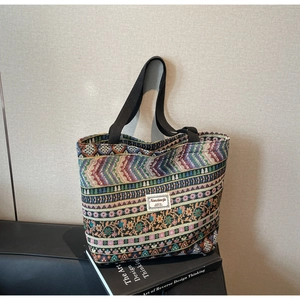 Detail view of Bohemian woven patterns and black fabric handles on a spacious tote bag
