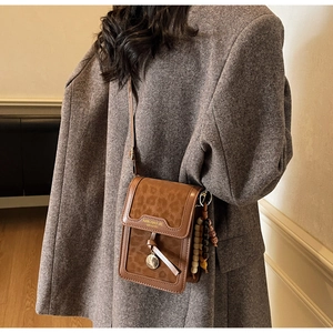 Detail showing brown leopard pattern phone bag with a metal logo and beaded tassel