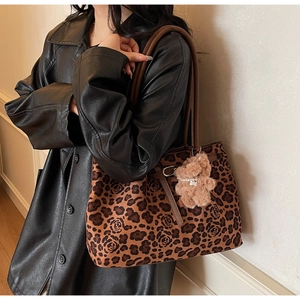 Detailed view of a leopard print tote bag with rose textures and a cute bear charm