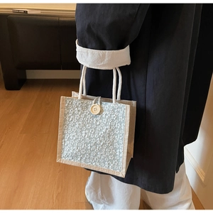 Detailed close-up of 3D floral embroidery and wooden button on the linen lunch bag