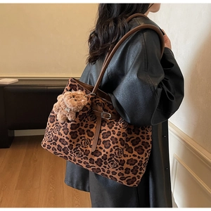 Leopard print tote bag with brown leather straps and plush bear charm detail