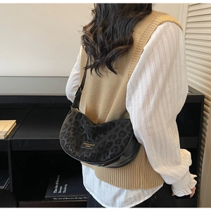 Détail du sac croissant à motif léopard avec bordure en cuir et logo en métal doré