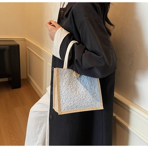 Detail of linen lunch bag with white floral pattern, rope handles and wooden button closure