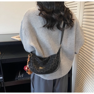 Détail du sac dumpling léopard gris avec pompon et breloque porté par un mannequin