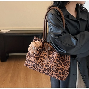 Detail of leopard and rose print tote bag with brown handles and plush bear charm