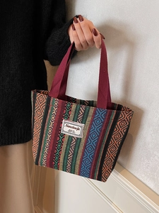 Ethnic style woven tote bag with colorful geometric stripes and red top handles