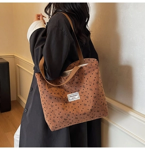 Detail of brown corduroy tote bag with black heart and bow prints and brand label