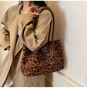 Detail of leopard and rose print tote bag with brown leather straps on a trench coat