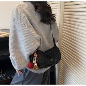 Vue détaillée du sac croissant noir à motif léopard avec un charm pompon coloré